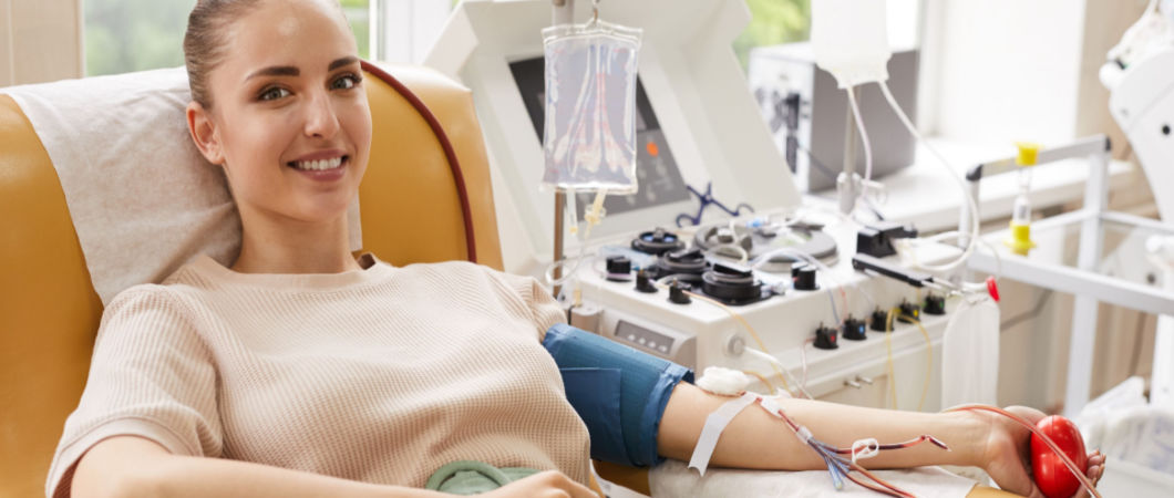 young woman with bouncy ball in hand donating blood at hospital