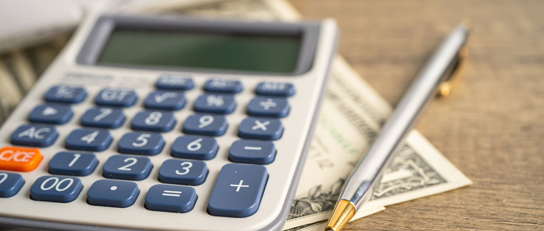calculator pen and dollar banknotes on table