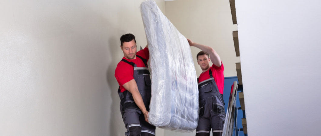 men in uniform carrying mattress downward