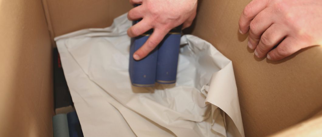 man laying books into a moving box