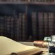 inkwell with feather and vintage book on wooden table