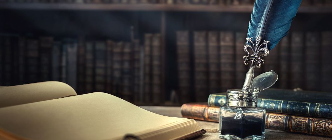inkwell with feather and vintage book on wooden table