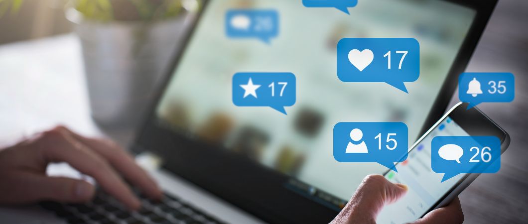 man using laptop and cellphone with different icons