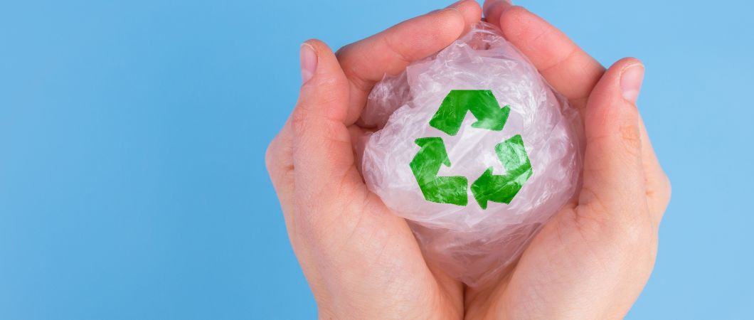 hand holding plastic with recycling logo