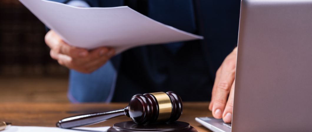 lawyer holding documents near gavel and laptop