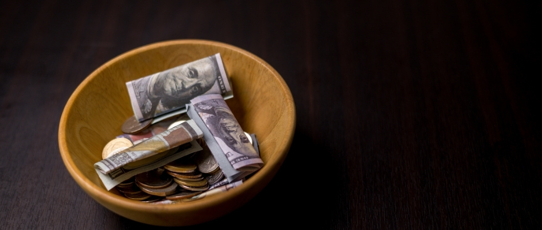 several coins and dollar bills in a bowl