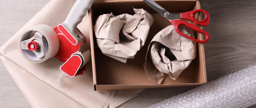 open box with wrapped items tapes scissors and bubble wrap