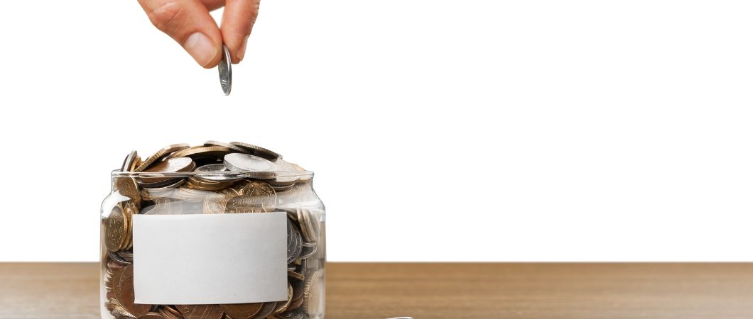 hand putting coins in glass jar