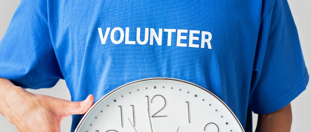 person holding wall clock in blue shirt with volunteer text