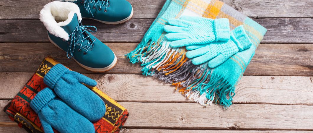 winter shoes gloves and scarves on wooden background